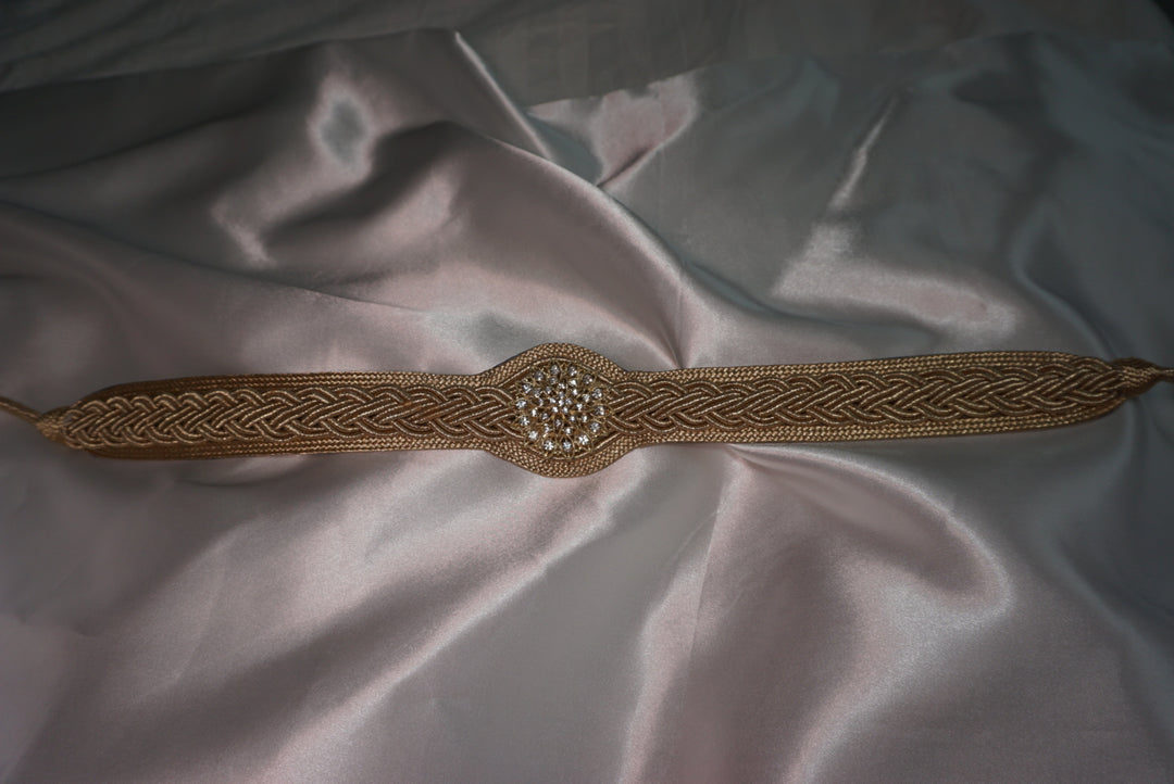 Gold belt with intricate designs on a textured fabric background