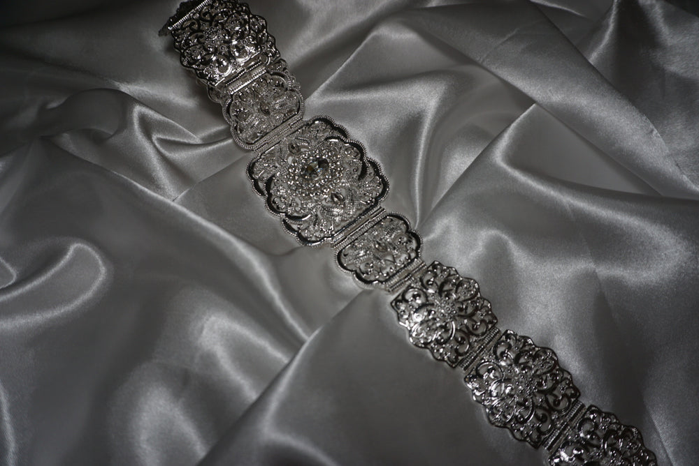 Silver Moroccan waist belt with intricate filigree design and crystal detailing – bridal and occasion belt for kaftans and abayas on satin background