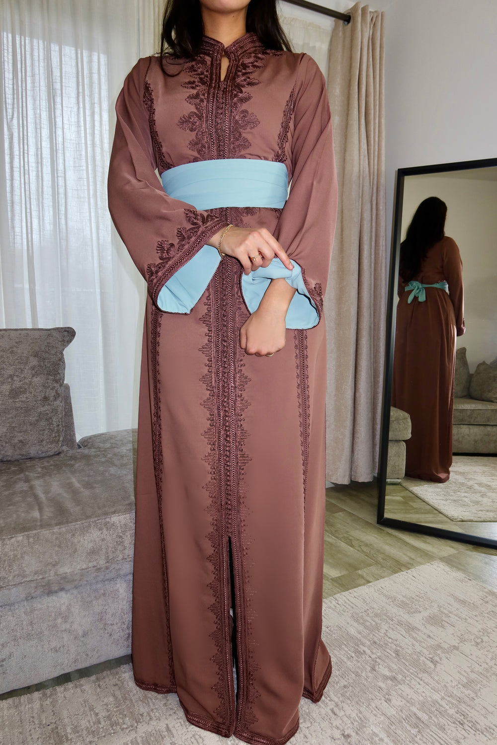 A woman wearing an olive green traditional Moroccan caftan with handcrafted embroidery and a flattering silhouette.